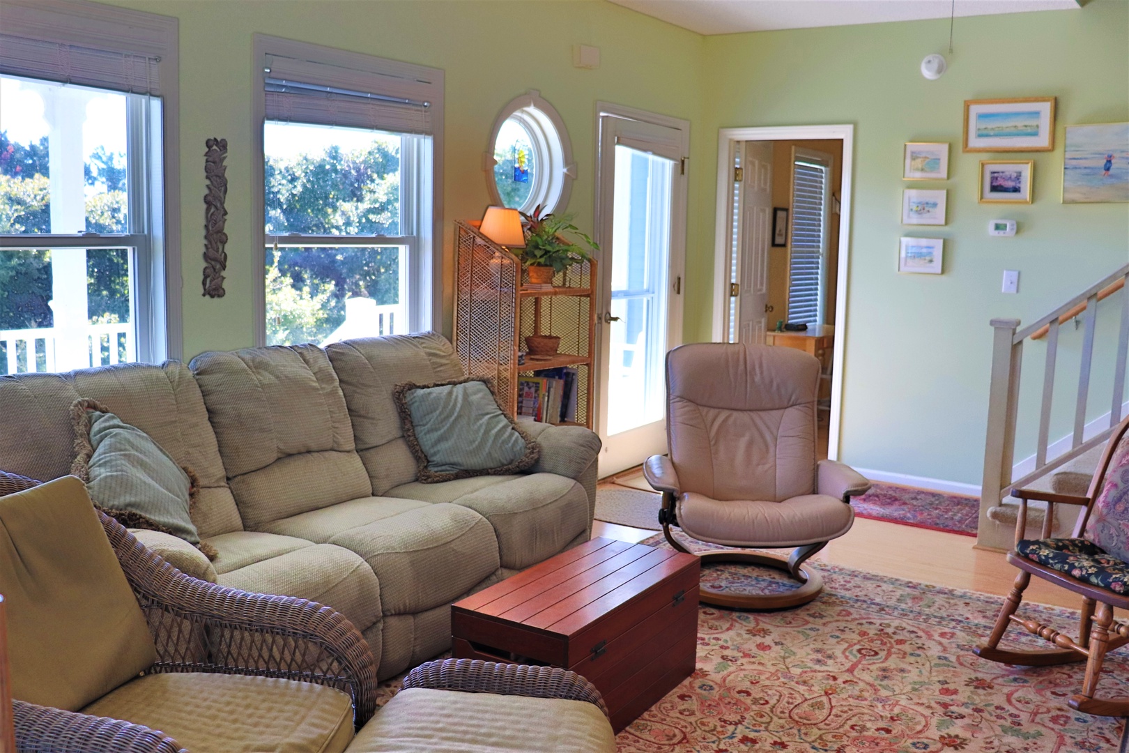 Sink into the plush sofas and unwind in this bright living room, where large windows frame leafy views and coastal art creates your peaceful retreat.