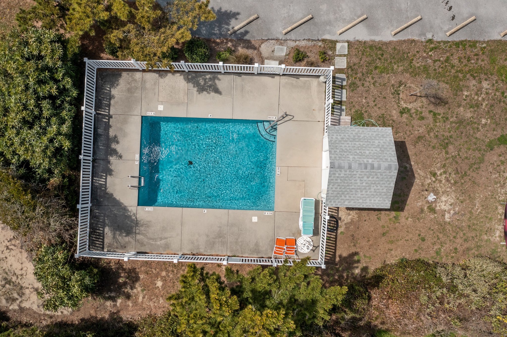 Aerial view of the property showcasing a pristine swimming pool surrounded by spacious deck areas and natural landscape.