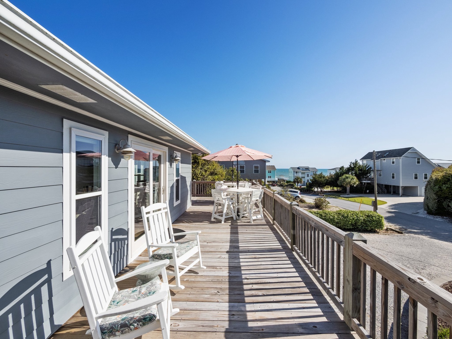 Expansive deck with ocean glimpses and coastal neighborhood views creates the perfect setting for morning coffee or sunset dining.