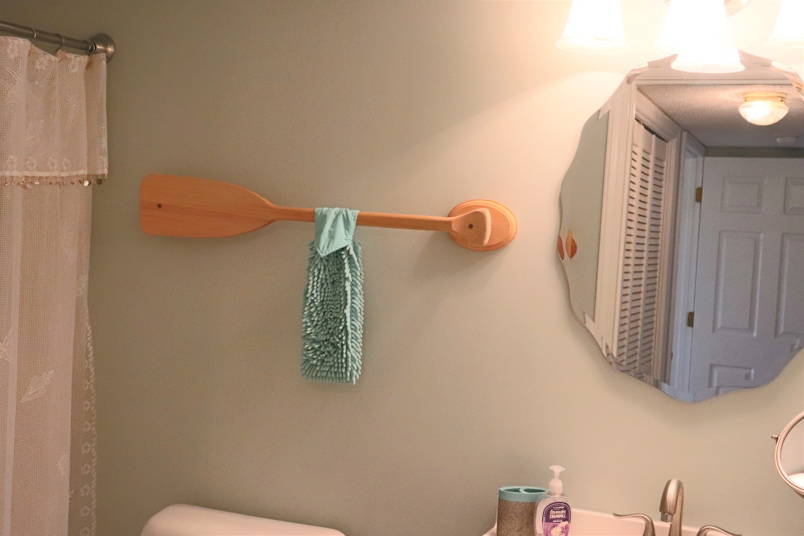 Your nautical-themed bathroom features charming coastal touches like an oar towel rack and soft lighting for a relaxing evening routine.