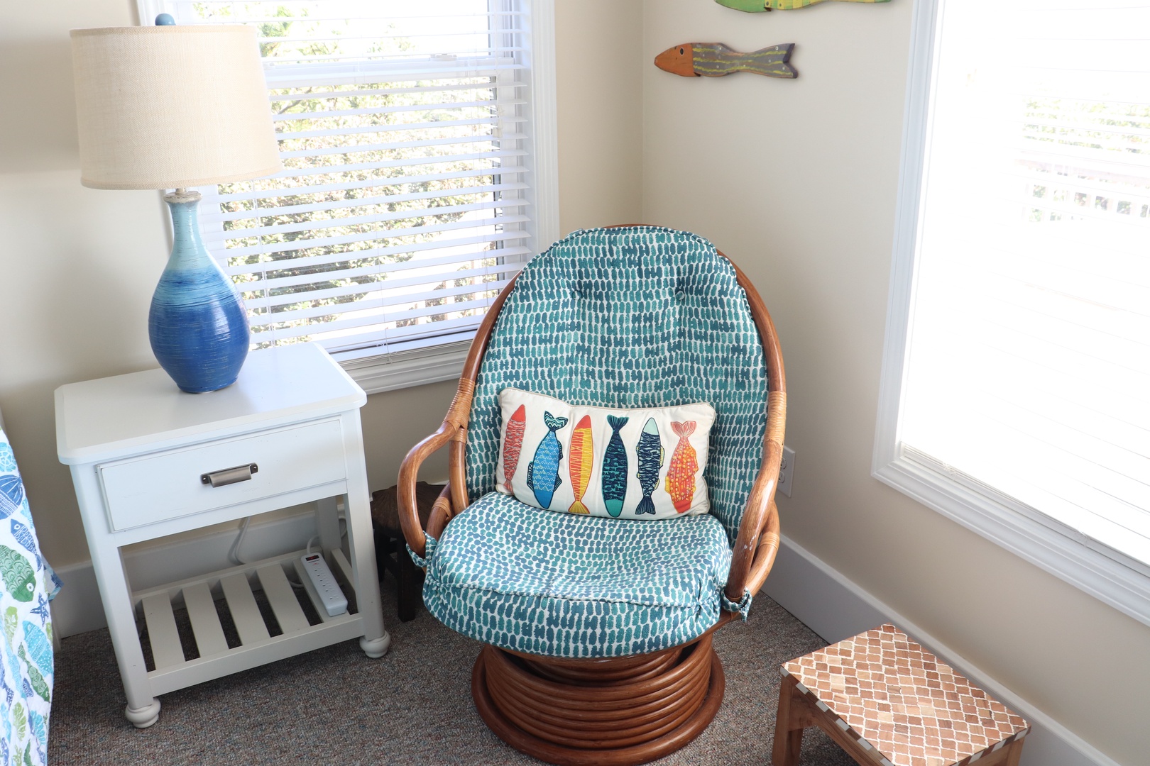 Curl up in your cozy corner chair with coastal charm, where cheerful fish pillows and ocean-blue hues create the perfect reading nook.