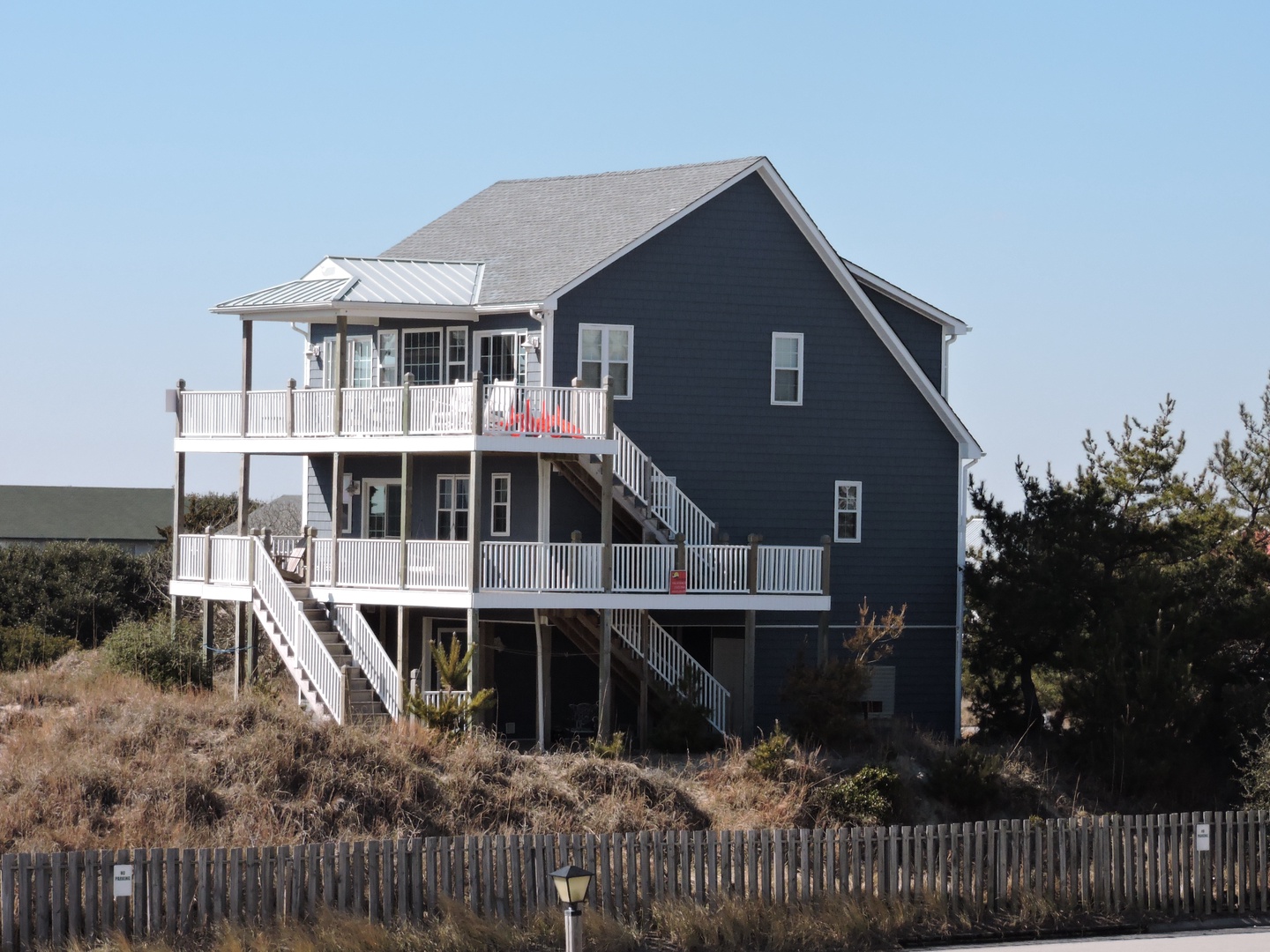 Charming coastal house with wraparound porches and beach access walkway.