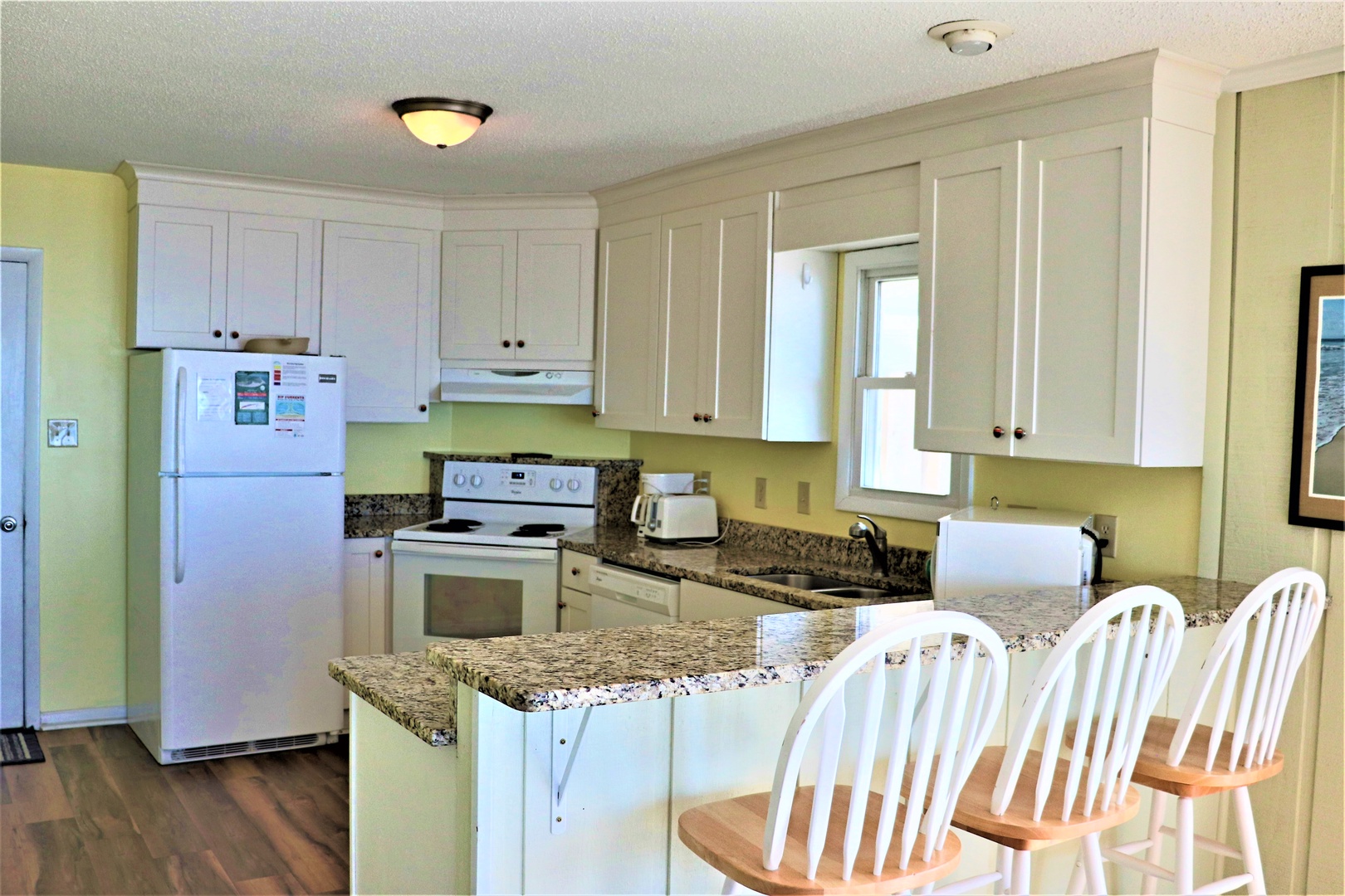 Your bright, fully-equipped kitchen welcomes you with granite counters, white cabinets, and cheerful yellow walls—perfect for cooking memorable vacation meals together.