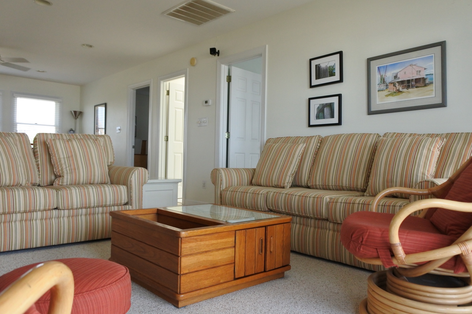 Relax in your comfortable living space with plush striped sofas, warm wooden coffee table, and original artwork adorning clean white walls.