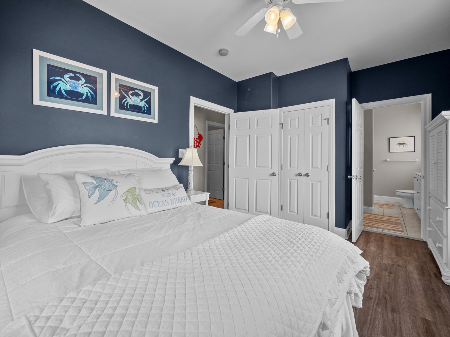 Drift off in your coastal-themed bedroom with crisp white linens and ocean artwork creating a peaceful retreat.