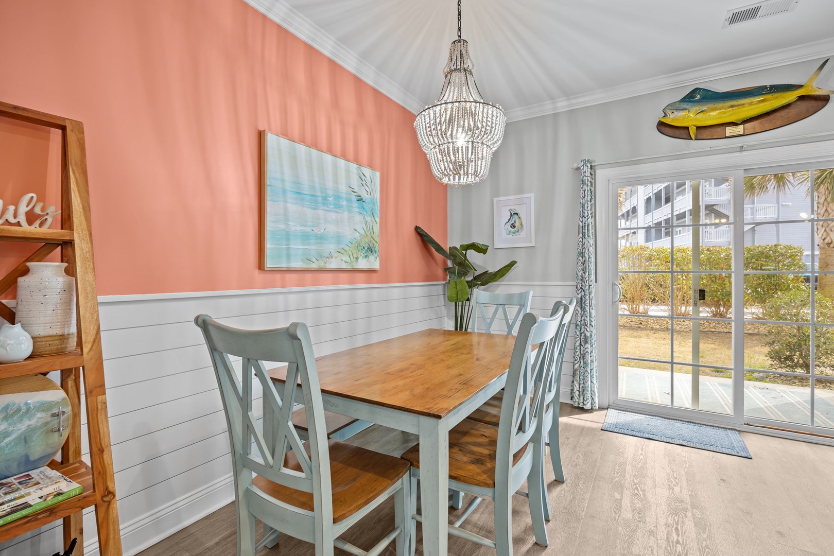 Gather around your coastal dining table where warm coral walls meet crisp white shiplap, creating the perfect backdrop for memorable meals together.