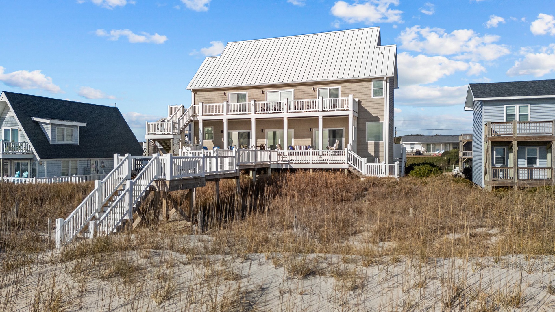 Beachfront vacation home with elevated decks and direct beach access via private walkway through coastal dunes.