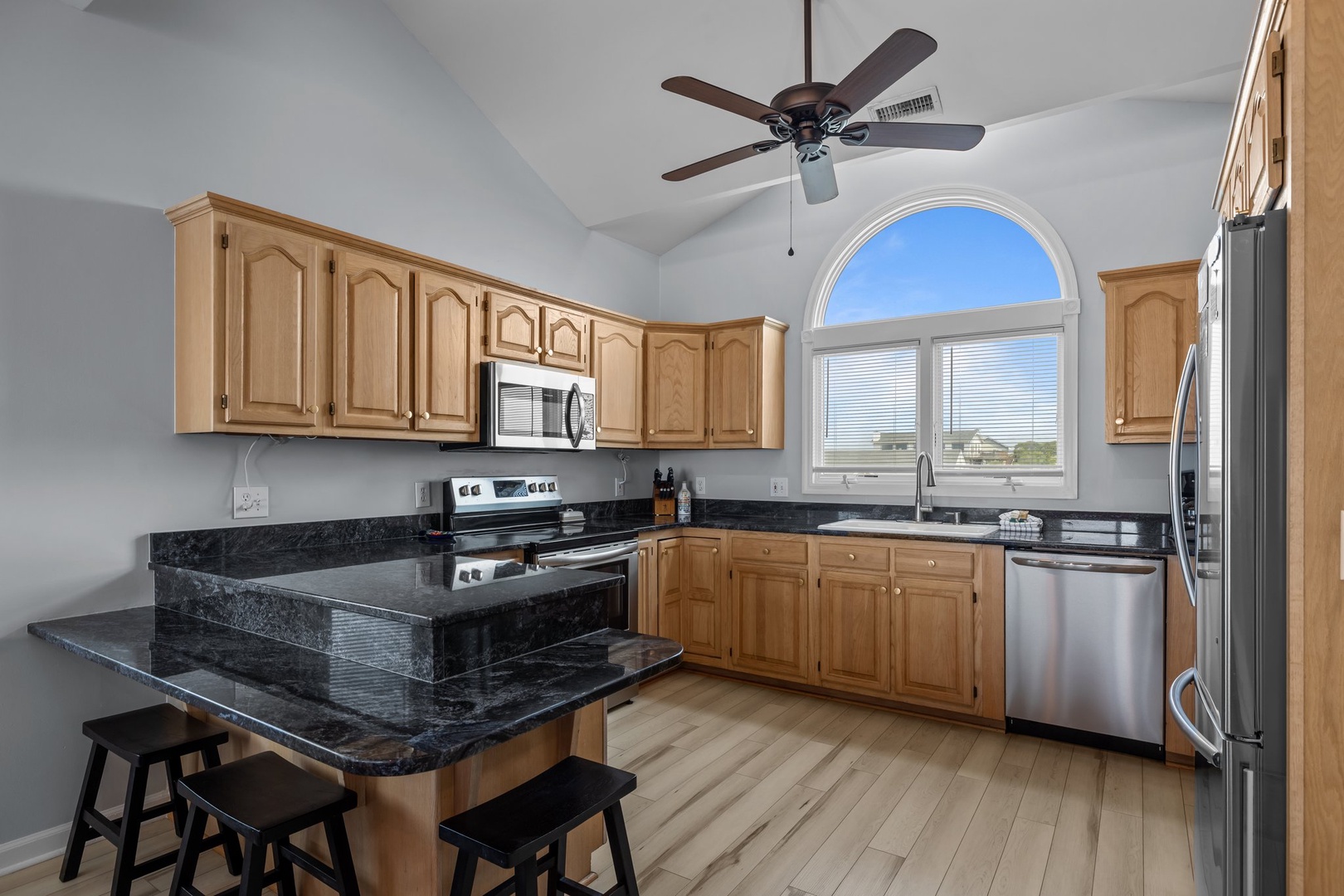 Your spacious kitchen awaits with granite counters, stainless appliances, and an elegant arched window overlooking scenic views.