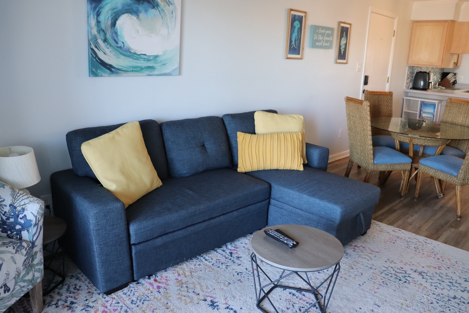 Sink into the plush navy sectional sofa where ocean-inspired art and sunny yellow accents create your perfect seaside retreat.