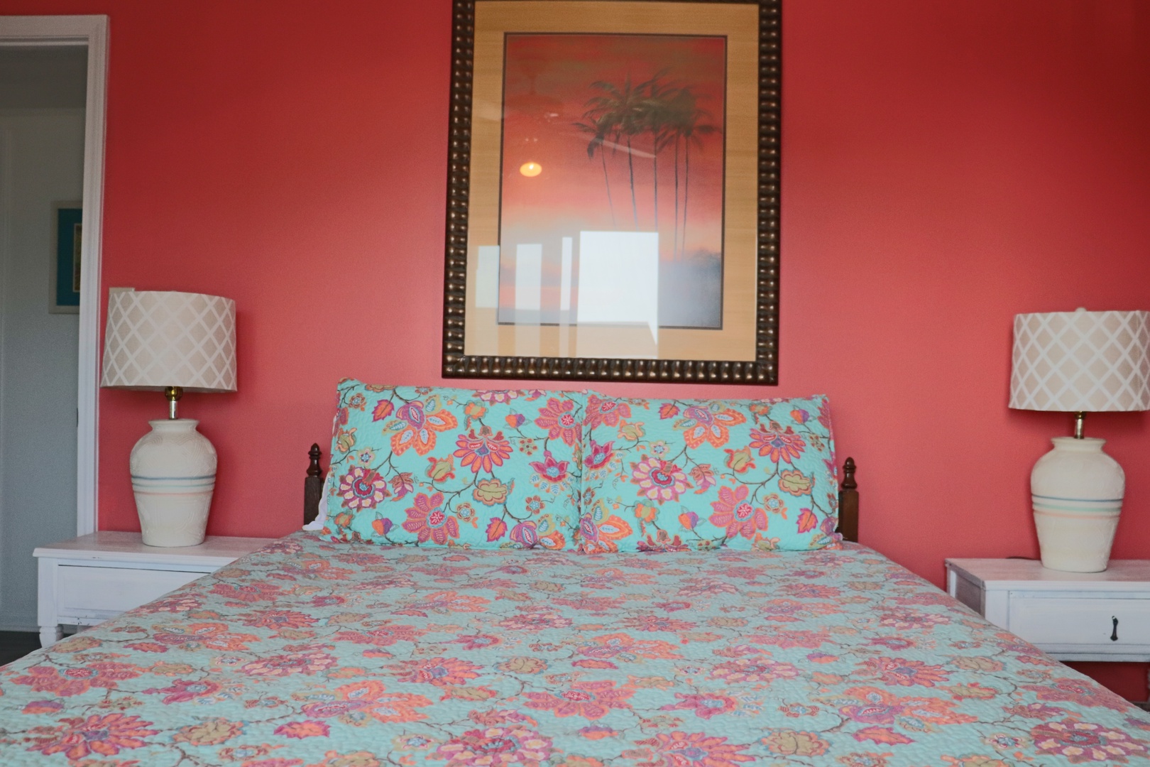 Drift off to sleep in this vibrant bedroom featuring tropical sunset artwork and cheerful floral bedding that creates your perfect island escape.