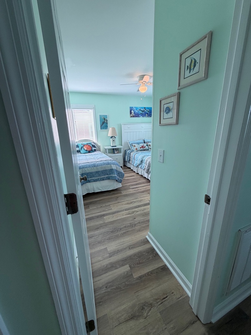 Unwind in your peaceful bedroom with coastal artwork and warm wood flooring creating a soothing seaside retreat.
