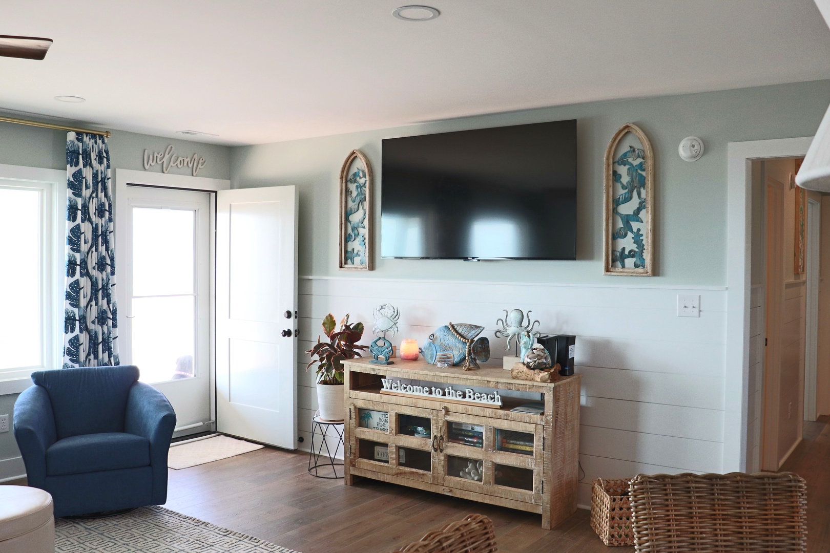 Unwind in your coastal living room where soothing blue tones and beach-inspired decor create the perfect atmosphere for movie nights.