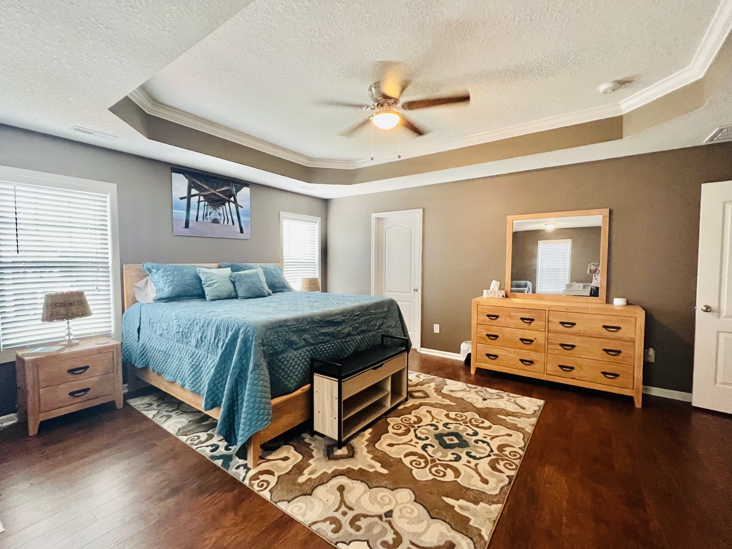 Unwind in your spacious master bedroom with teal linens, elegant tray ceiling, and rich hardwood floors.