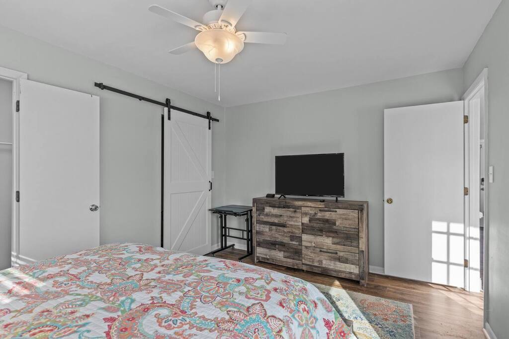 Relax in your peaceful bedroom featuring charming barn doors, comfortable bedding, and modern amenities like a flat-screen TV for cozy evenings.