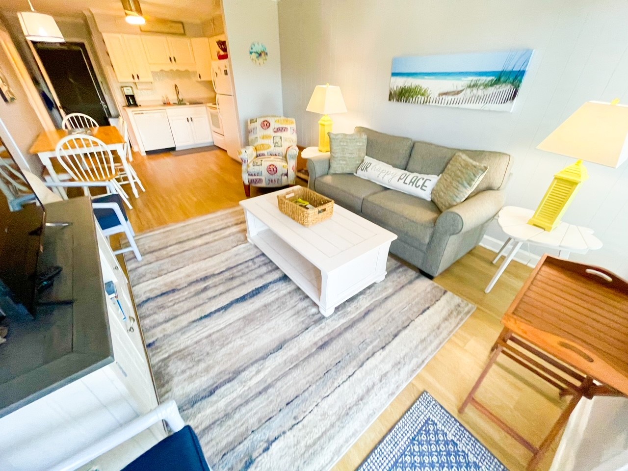 Unwind on your comfortable sofa while enjoying coastal artwork that sets the perfect beach house mood in this bright, open living space.