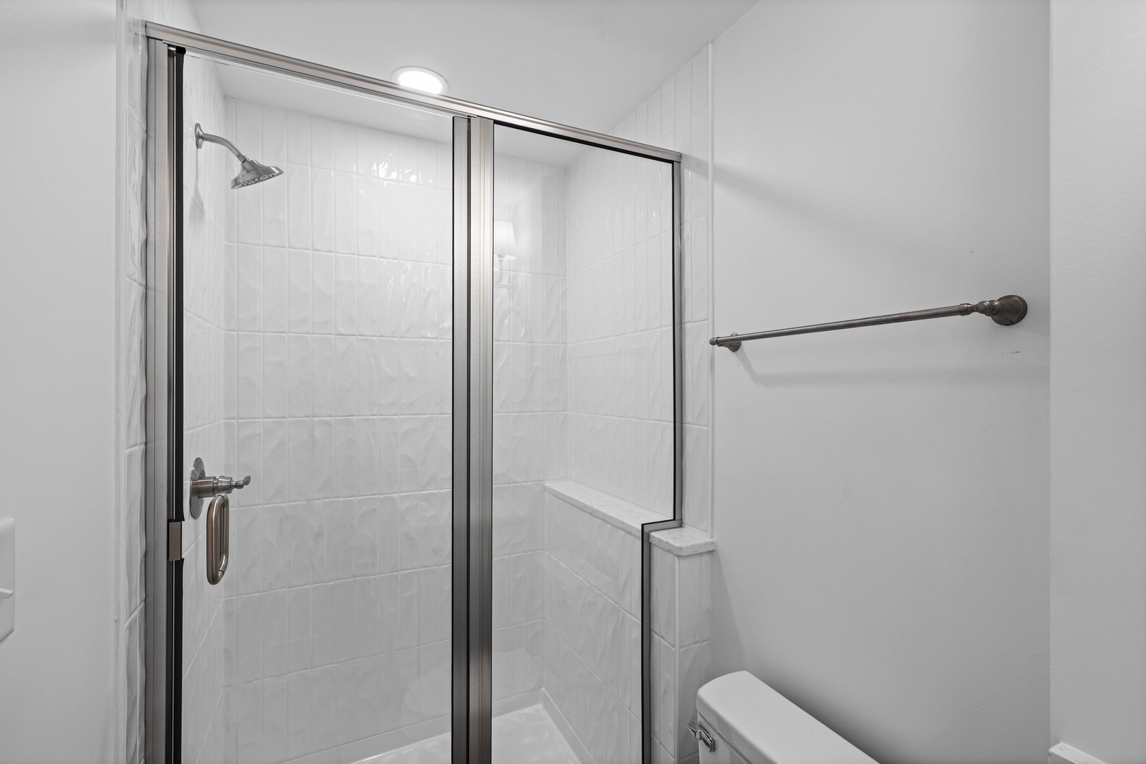 Step into your pristine shower with sleek glass doors and rainfall showerhead for a refreshing start to your day.