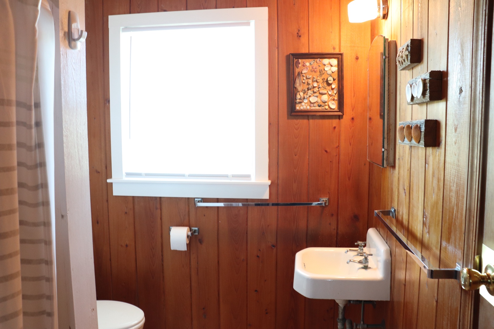 Rustic wooden walls and natural light create a cozy bathroom retreat for your beach getaway.