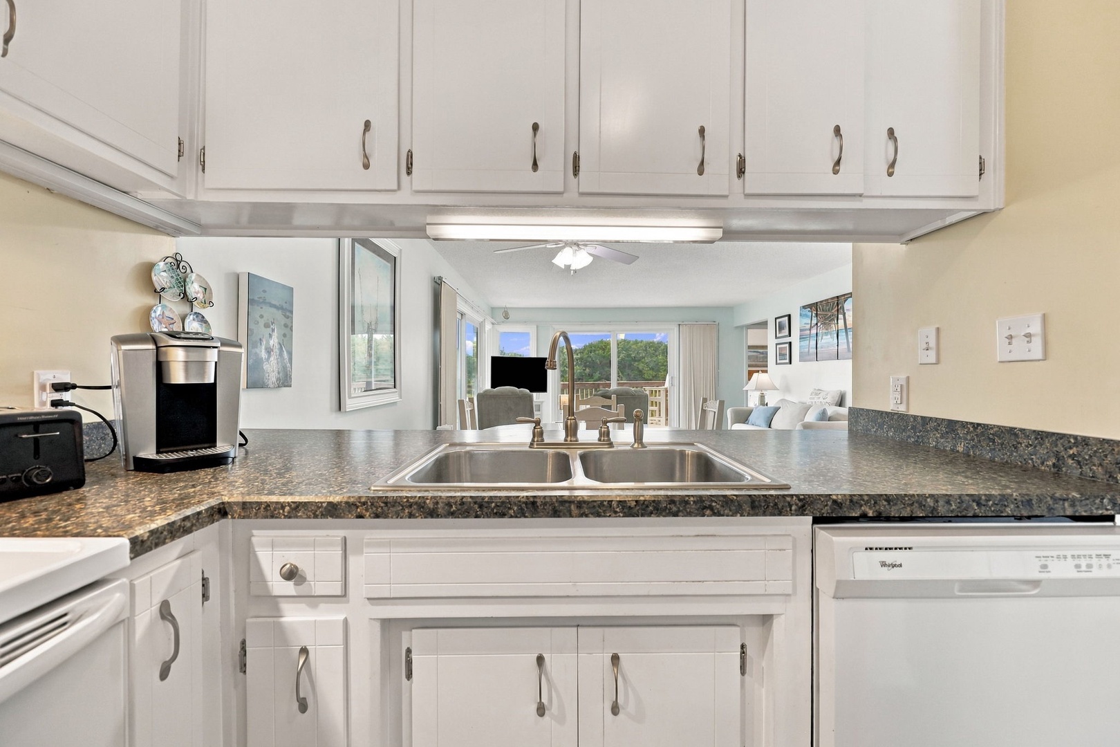 Your fully equipped kitchen opens to a bright, sun-filled living space where natural light pours through sliding glass doors, inviting you to enjoy seamless indoor-outdoor living.