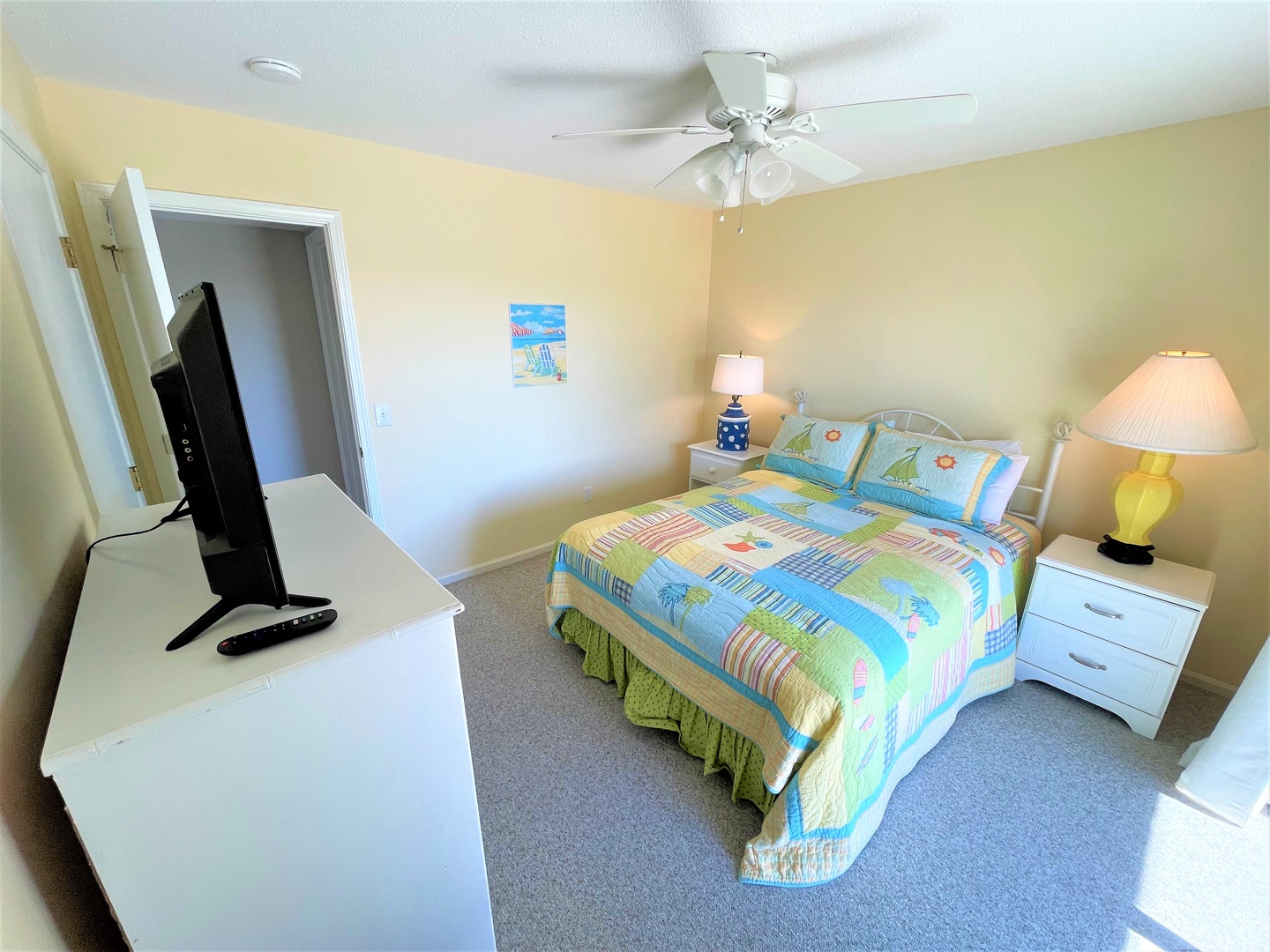 Relax in your bright bedroom featuring colorful beach-themed bedding, bedside lamps for evening reading, and your own TV for cozy nights in.