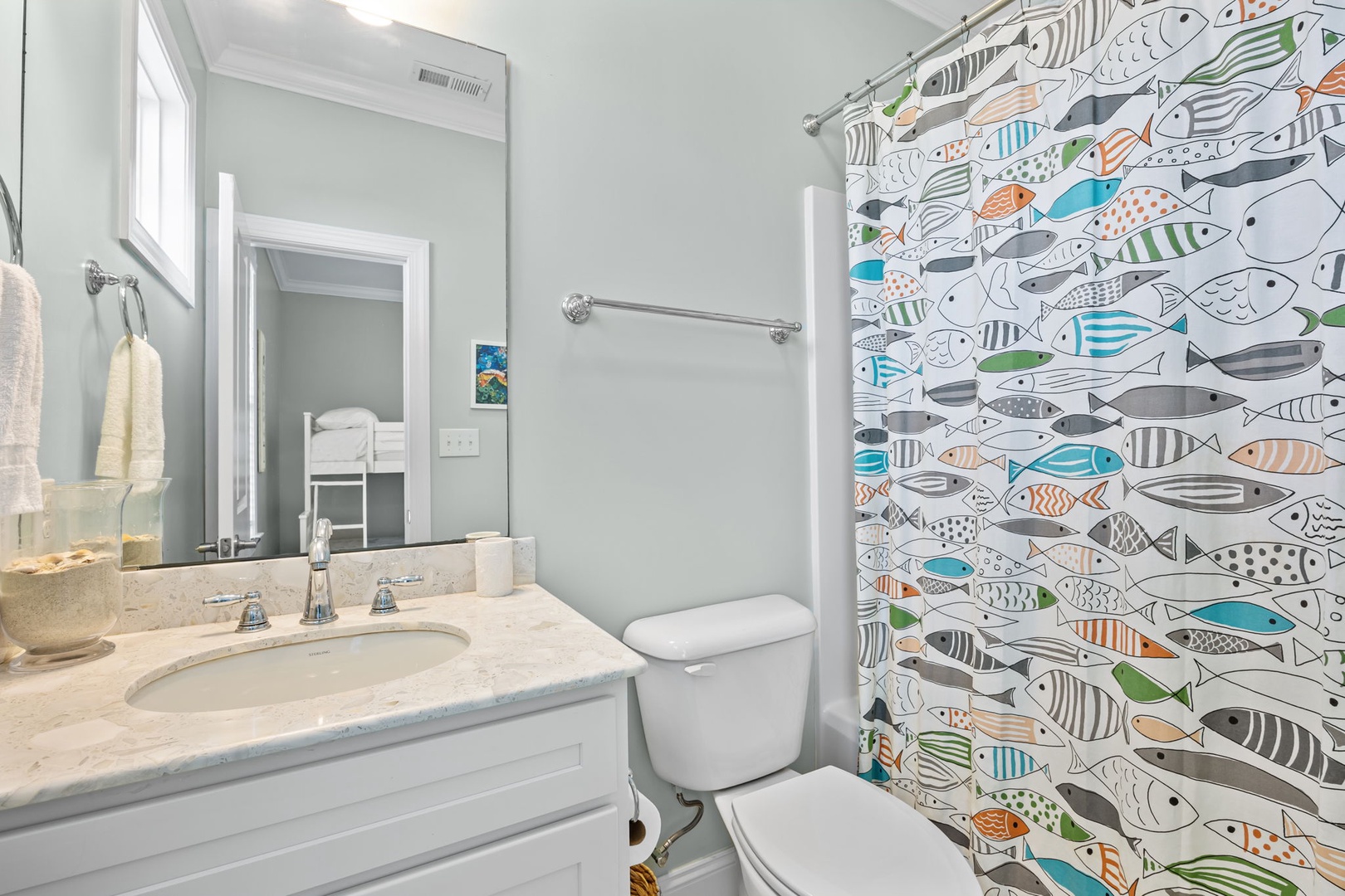 Freshen up in your bright bathroom featuring a whimsical fish-patterned shower curtain that adds coastal charm to your morning routine.