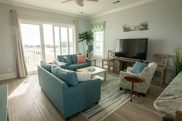 Relax in your bright coastal living room with comfortable seating and beach views from the sliding doors.