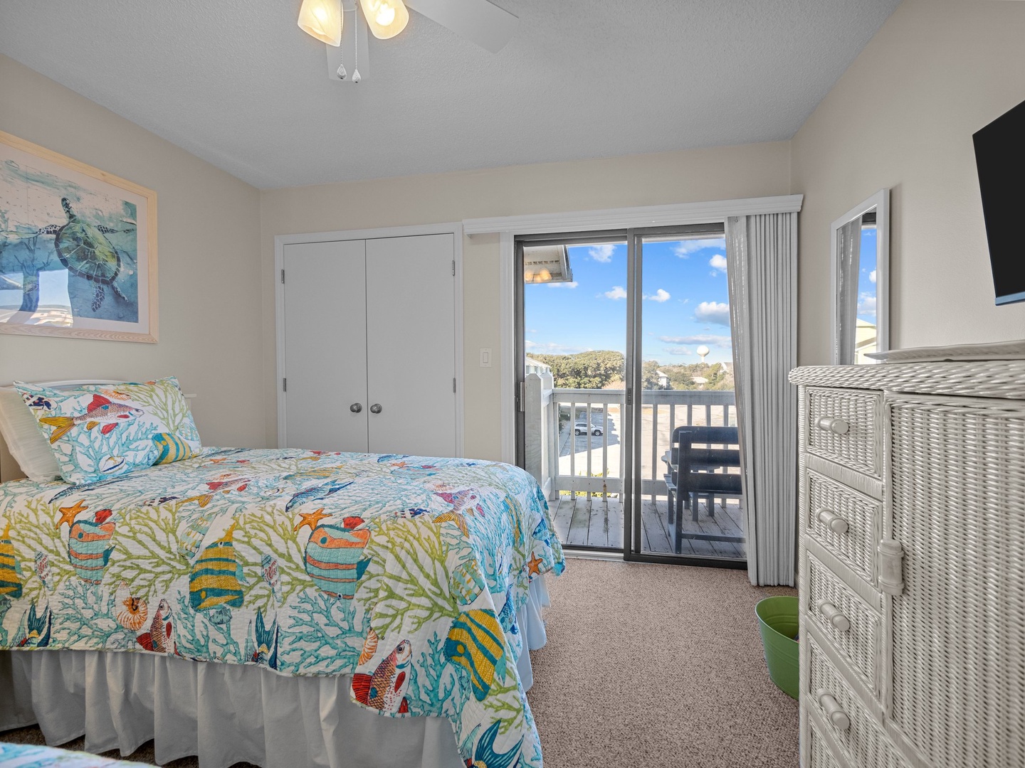 Your bright bedroom features cheerful tropical bedding and opens to a private balcony with scenic views beyond.