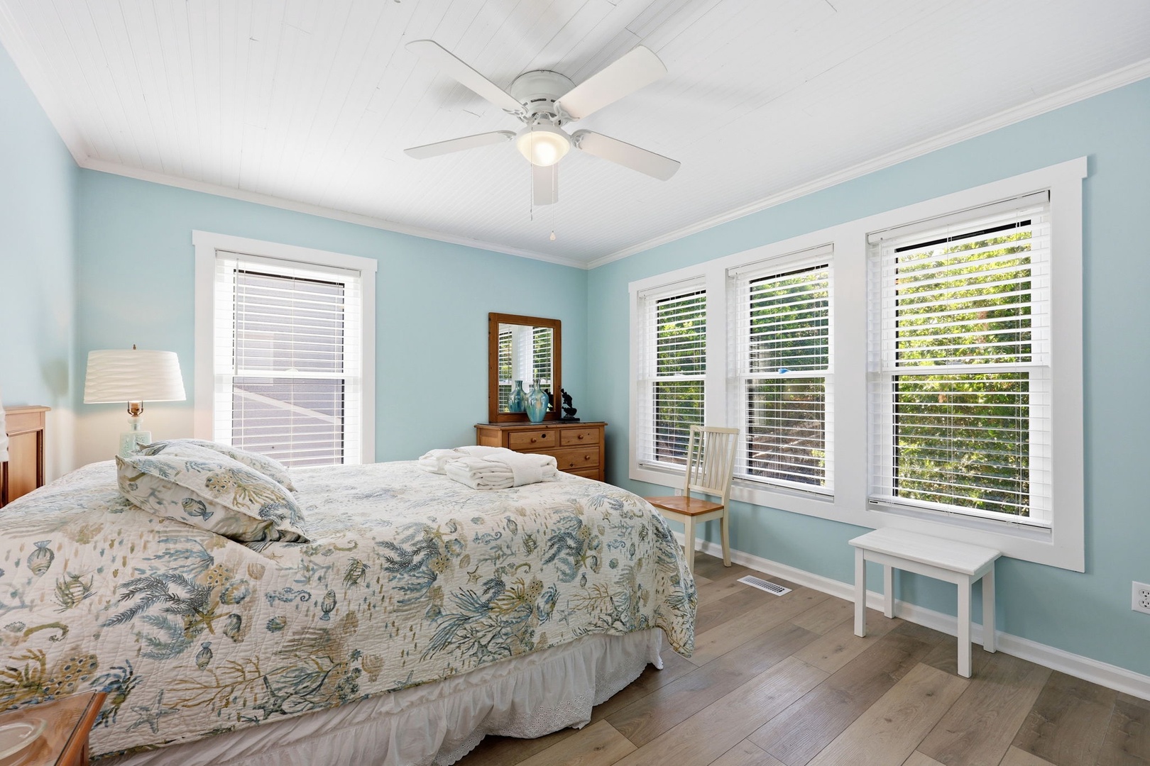 Drift off in this serene bedroom with calming coastal hues, soft linens, and natural light streaming through large windows. Your peaceful retreat awaits.
