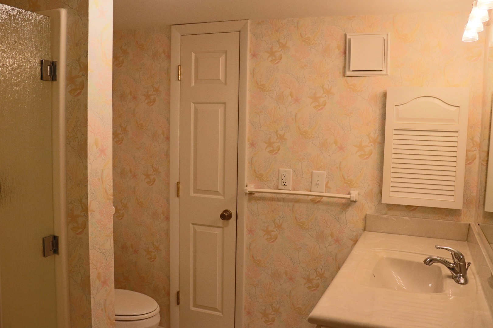 Your private bathroom features a refreshing shower, modern sink, and charming floral wallpaper that creates a cozy, homey atmosphere.