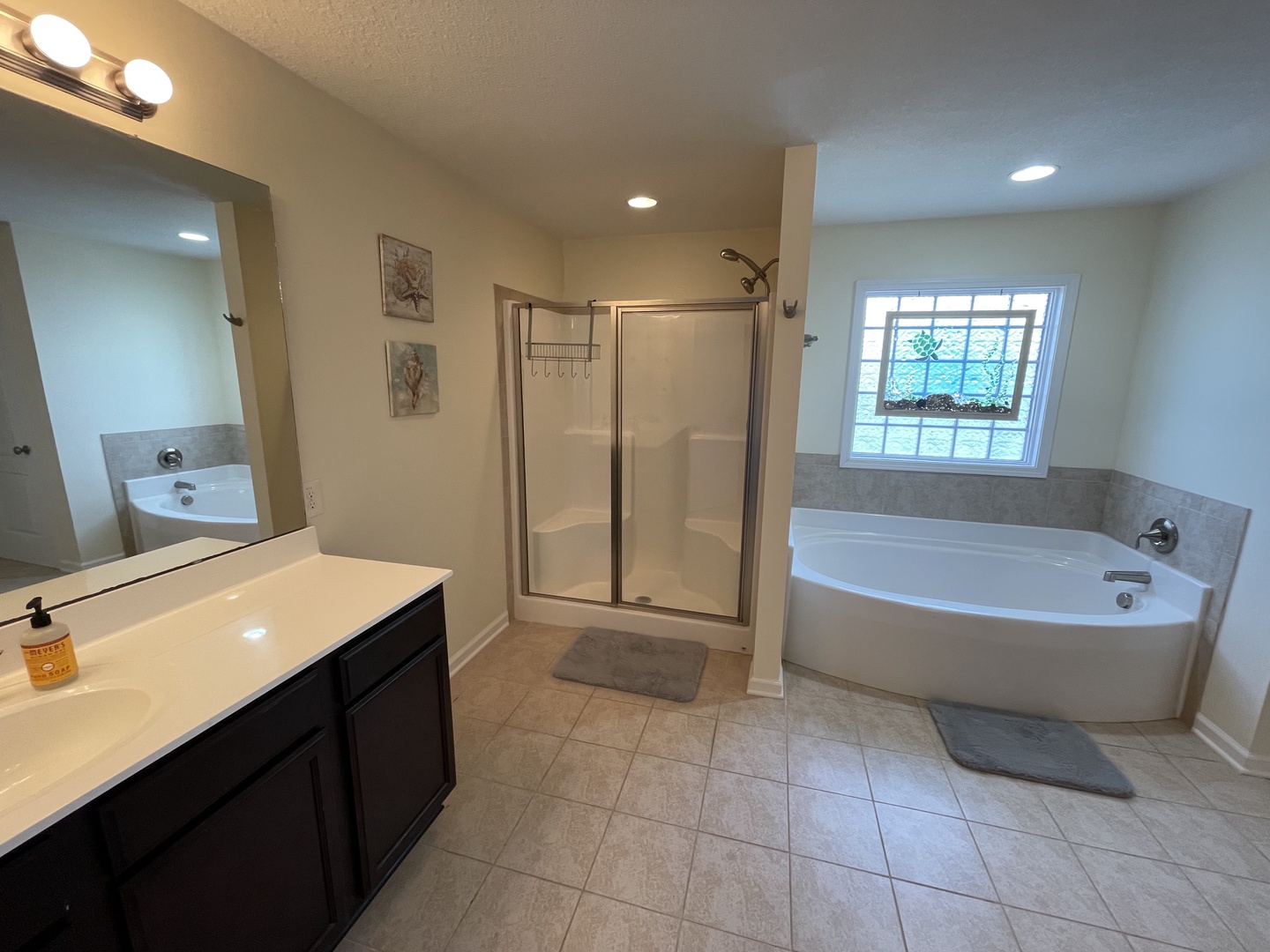 Unwind in your luxurious bathroom with dual vanities, a relaxing corner soaking tub, and spacious glass shower.