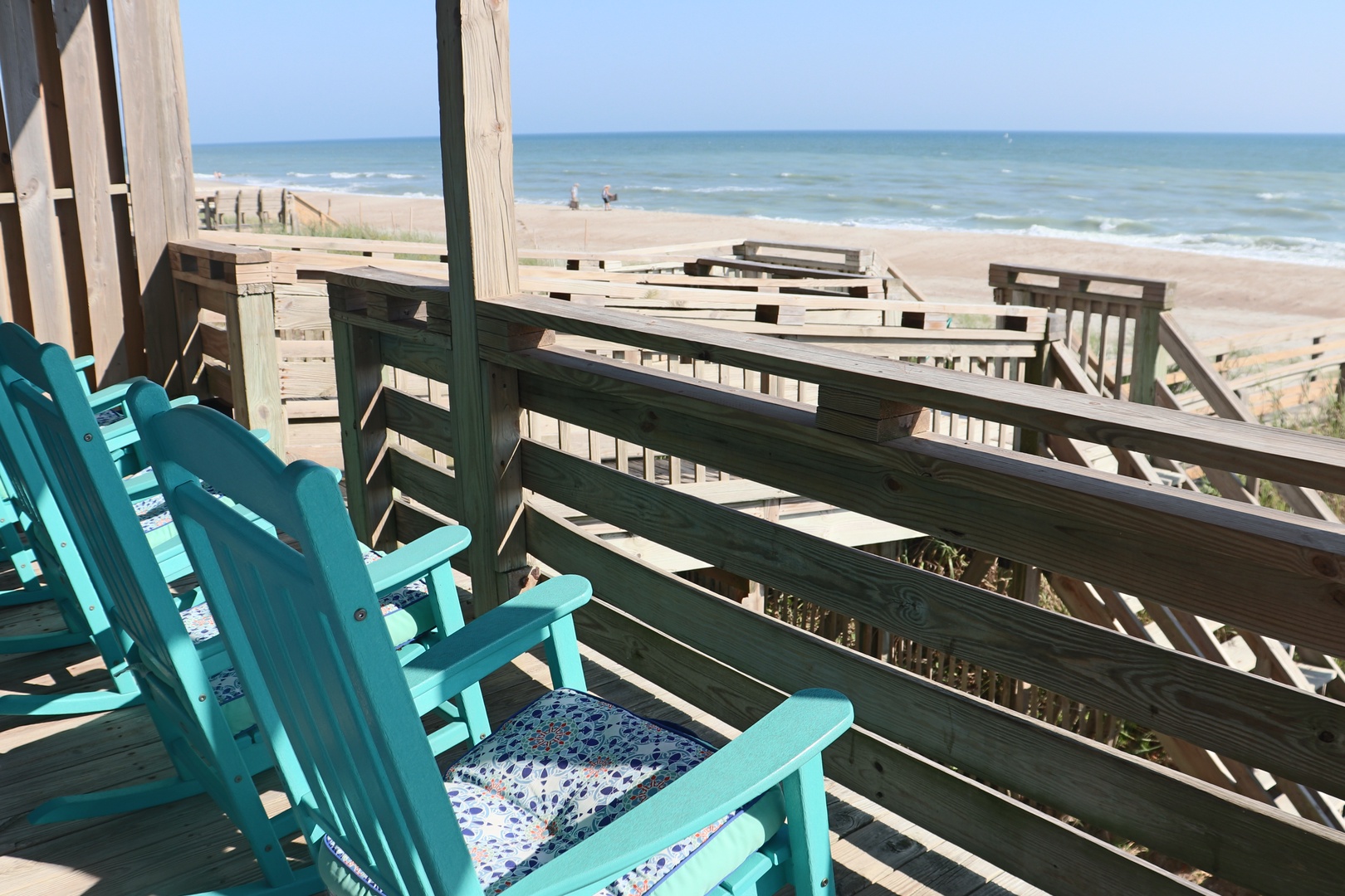 Step onto your private deck where turquoise chairs await your morning coffee ritual, framing endless ocean views and sandy shores.