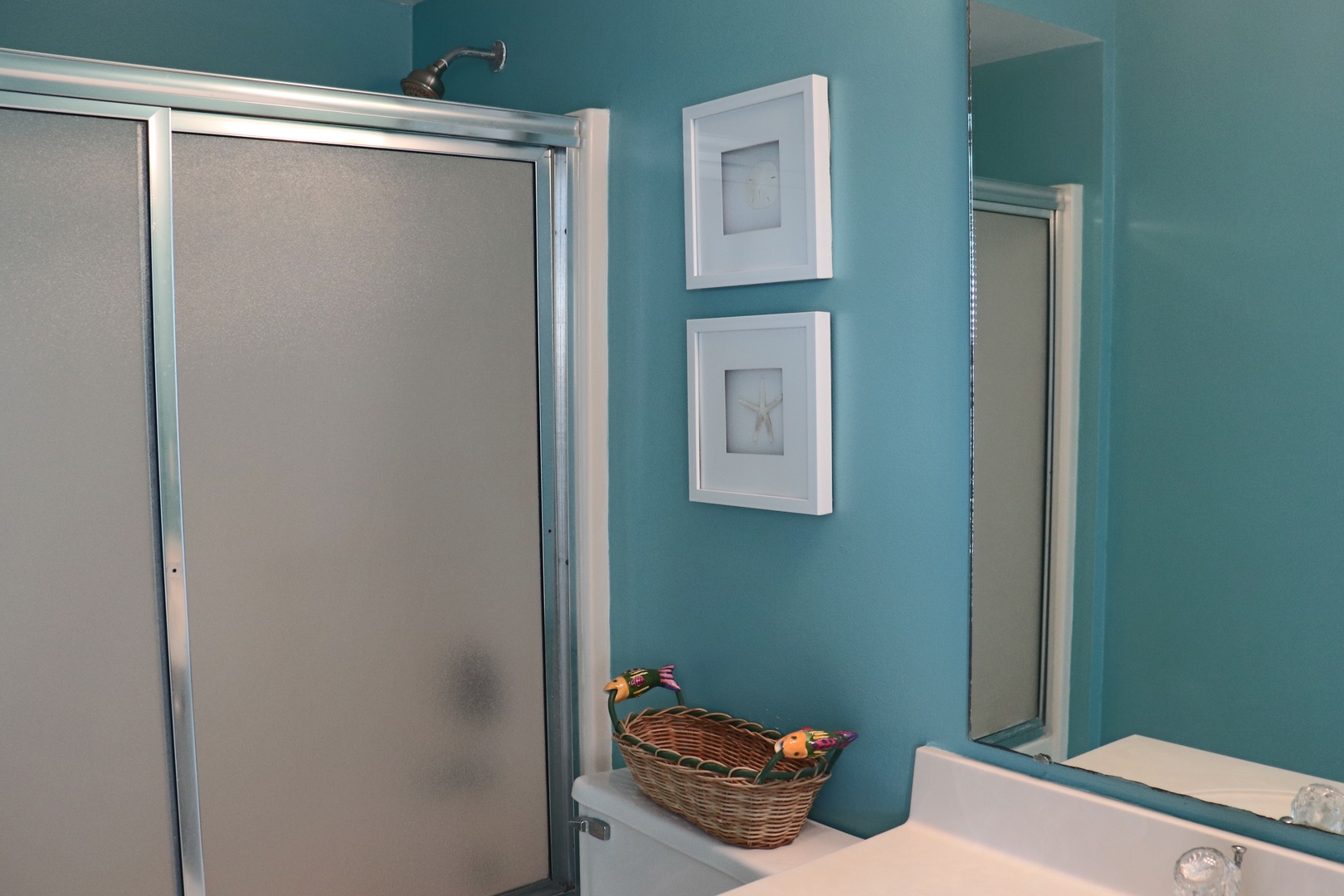 Step into your serene bathroom retreat with calming teal walls, modern glass shower, and thoughtful coastal touches.