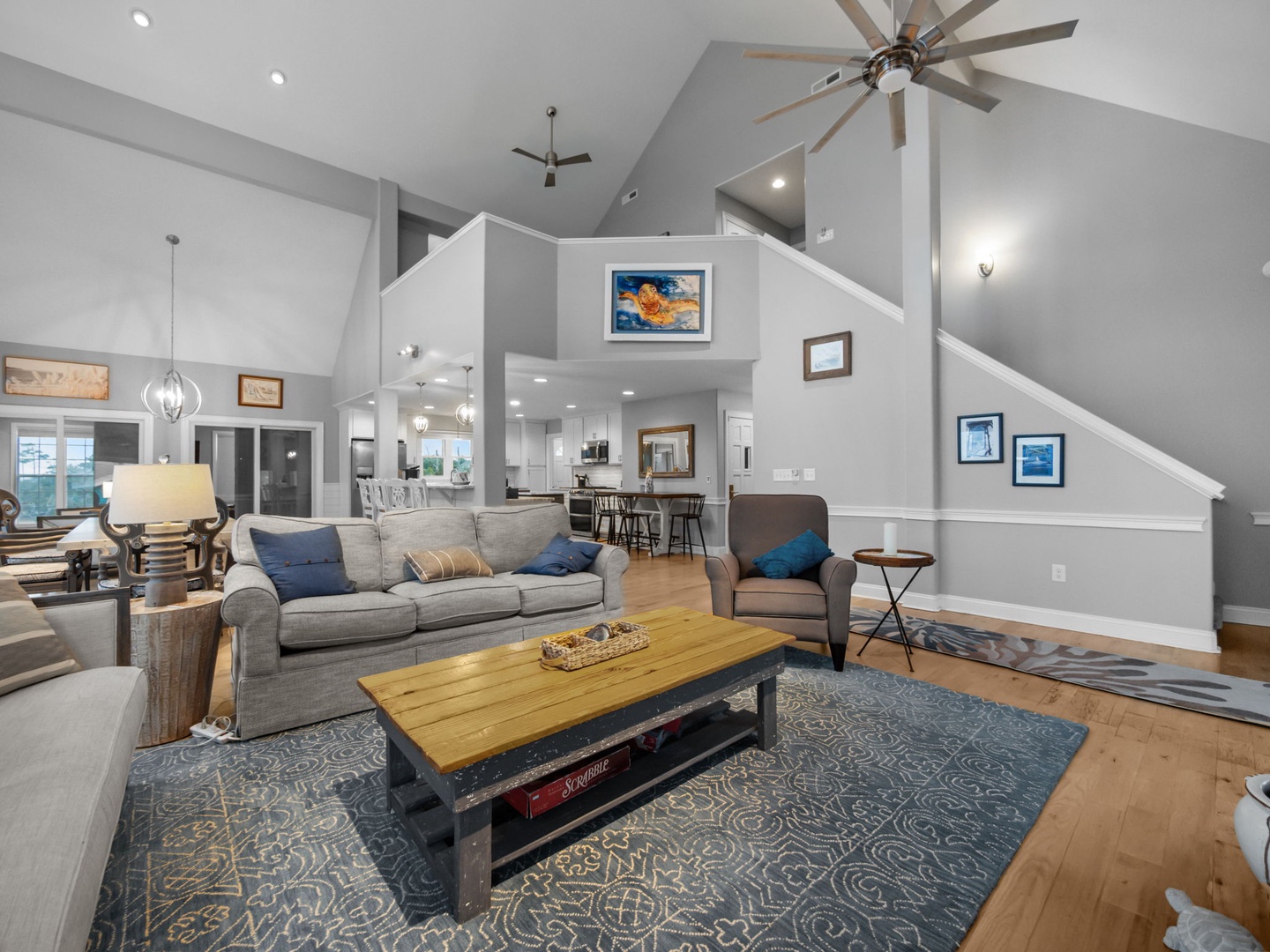 Unwind in your spacious living room with soaring ceilings, cozy grey sectional, and open flow to the kitchen.