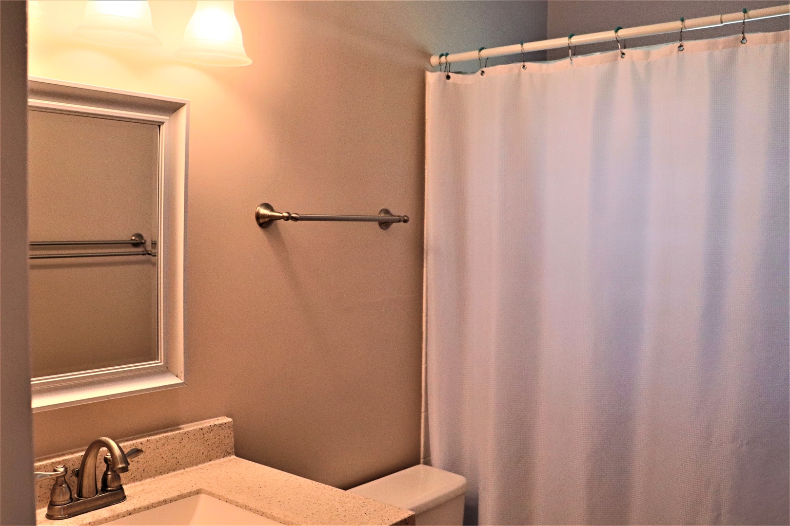 Step into your private bathroom featuring a spacious shower with crisp white curtain and convenient towel bar for your comfort.