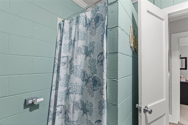 Step into your serene shower sanctuary with coastal charm, where calming sea-green shiplap and tropical curtains create your perfect morning retreat.
