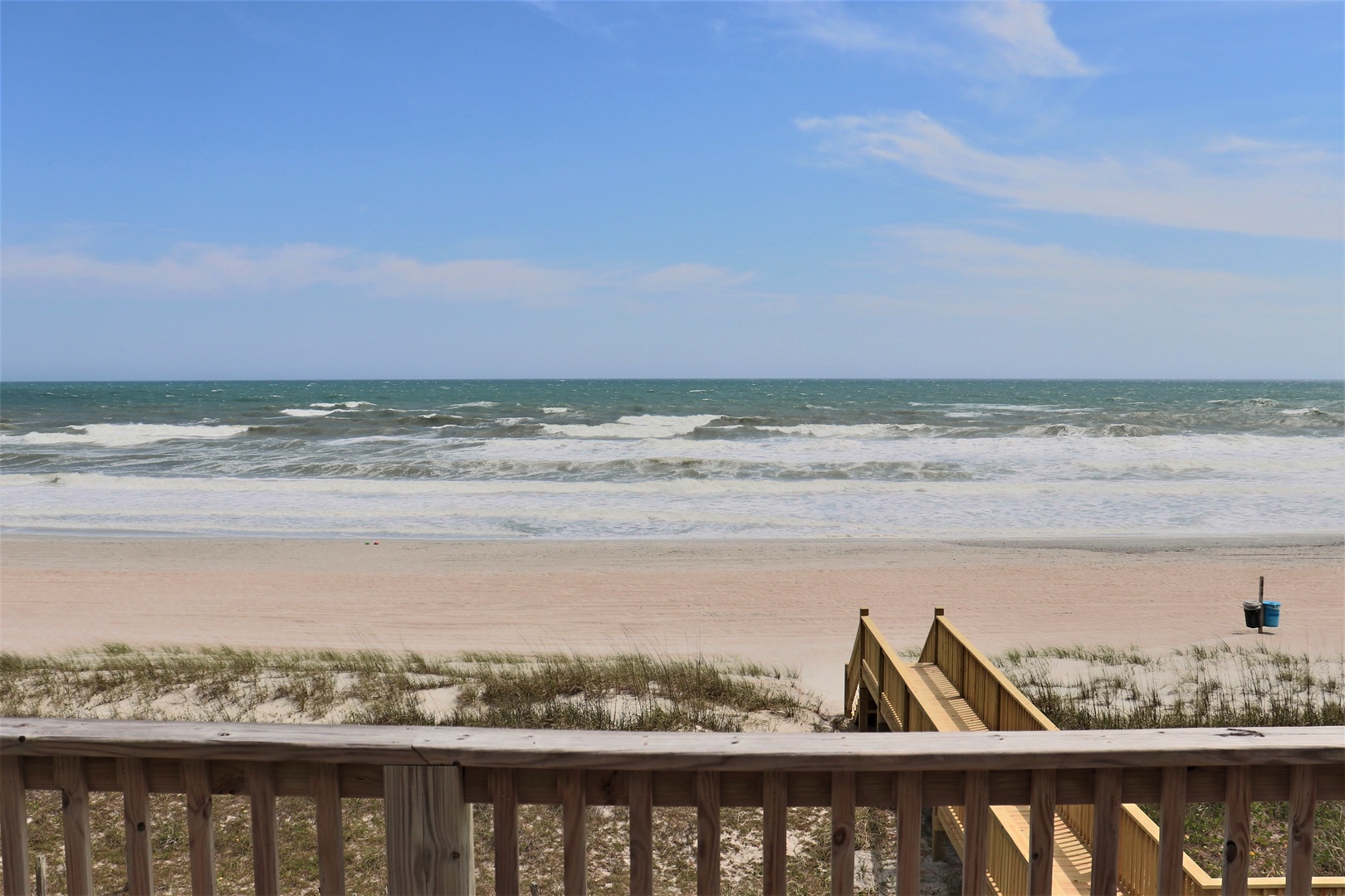 Direct beach access with ocean waves and sandy shoreline visible from the property deck.