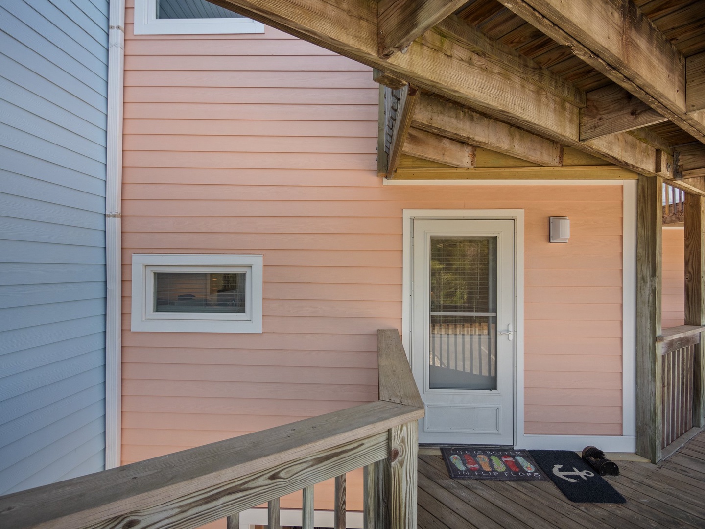 Charming coral-colored entrance welcomes you with a covered porch and coastal-inspired design details.