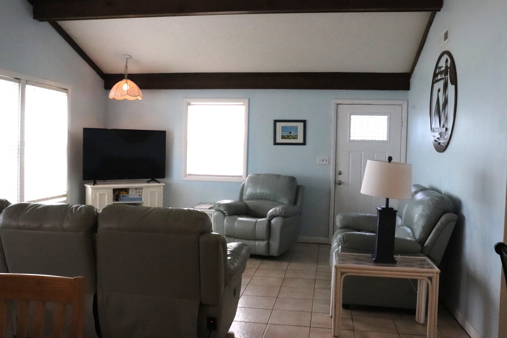 Sink into plush leather seating as natural light fills your welcoming living space. Cozy up for movie nights with full entertainment, or simply unwind in the calming atmosphere of your coastal retreat.