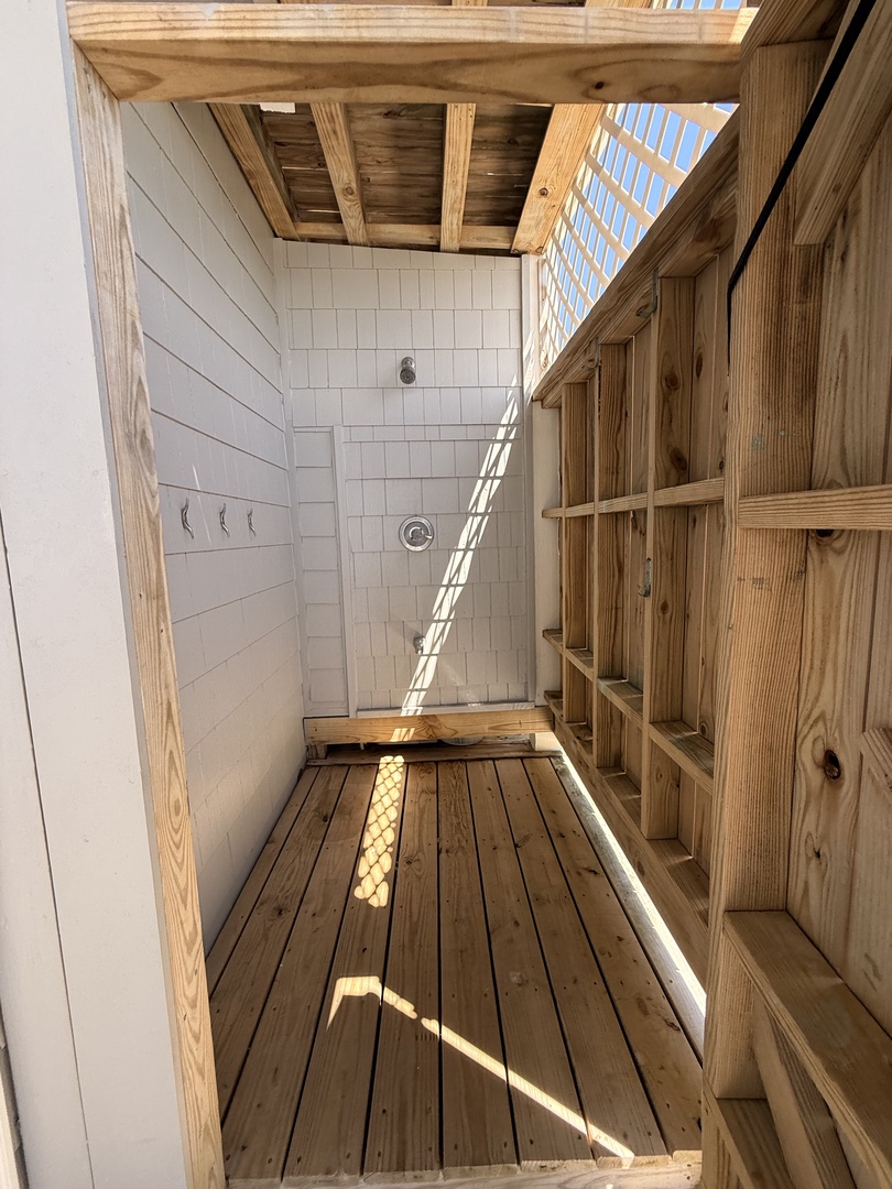 A private outdoor shower awaits with natural wood beams overhead and white tile walls, bringing fresh air to your rinse-off after a day of adventure.