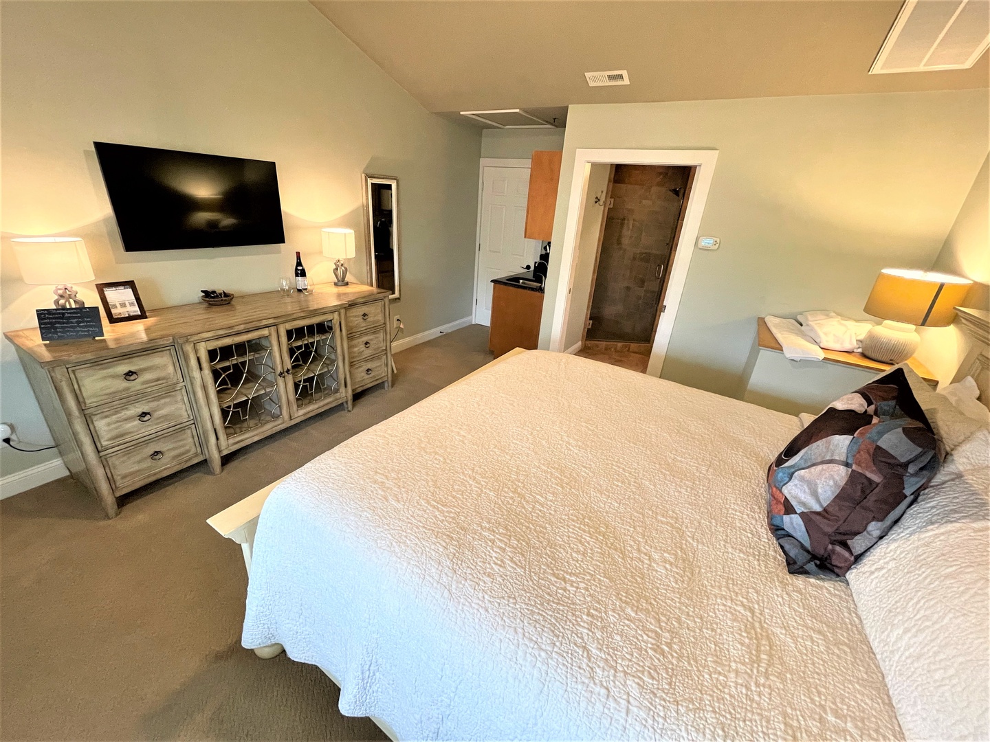 Relax in your spacious master suite with cozy bedding, entertainment center, and private ensuite bathroom for the perfect retreat.