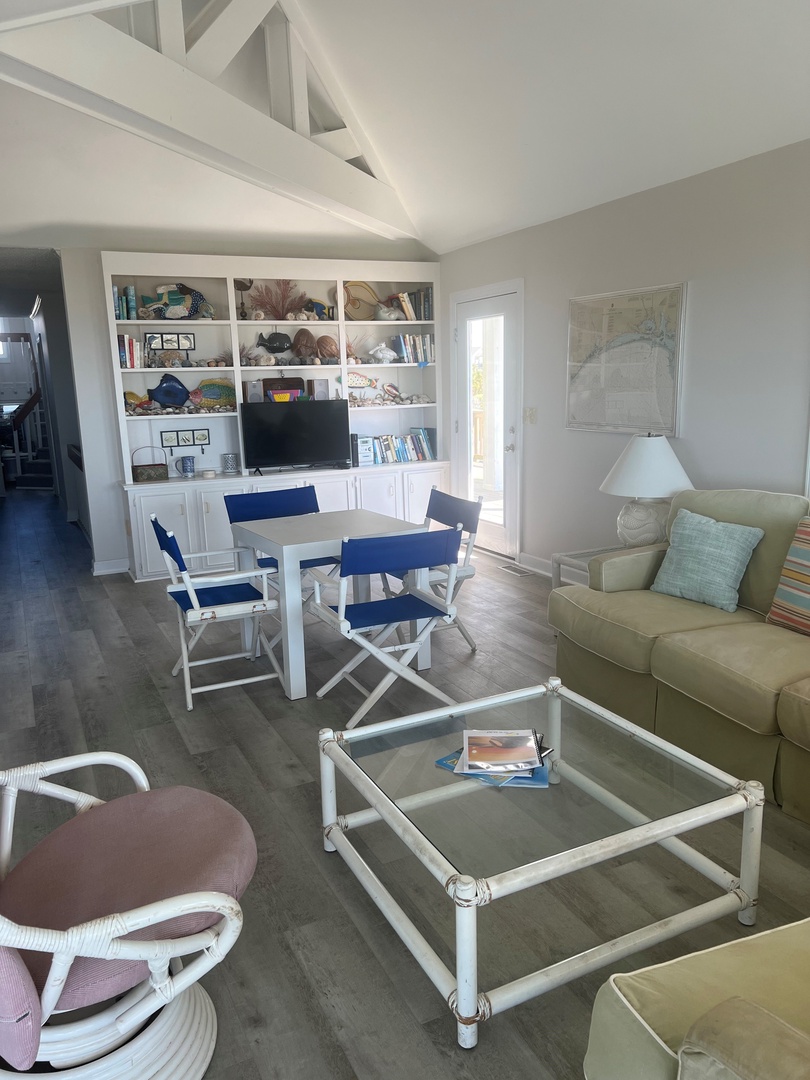Relax in your bright, airy living space featuring exposed beams, built-in entertainment center, and comfortable seating perfect for unwinding after beach days.