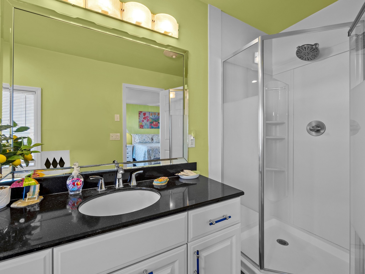 Refresh in your bright bathroom with modern shower, granite vanity, and cheerful green accents.