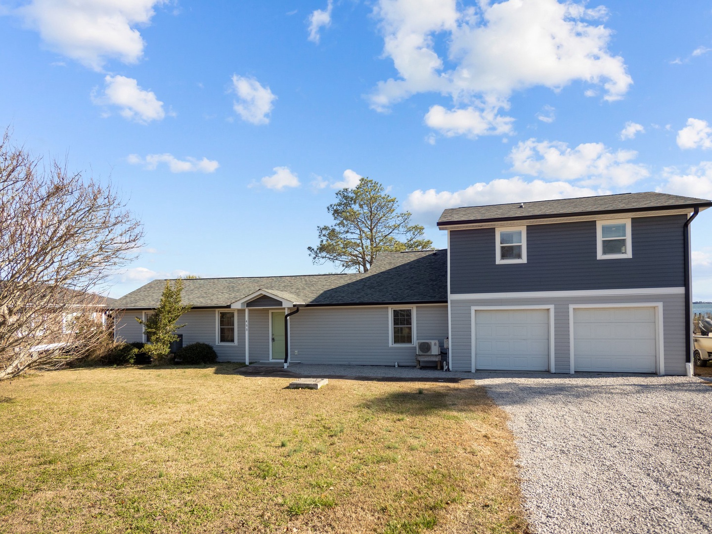 Spacious vacation home with two-car garage and open yard under bright blue skies.