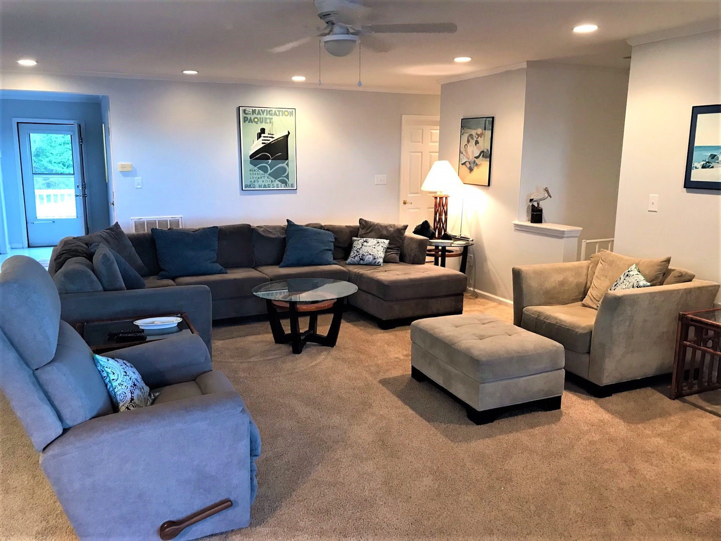 Sink into plush seating in this spacious living room, where nautical artwork and soft lighting create the perfect atmosphere for your relaxation.