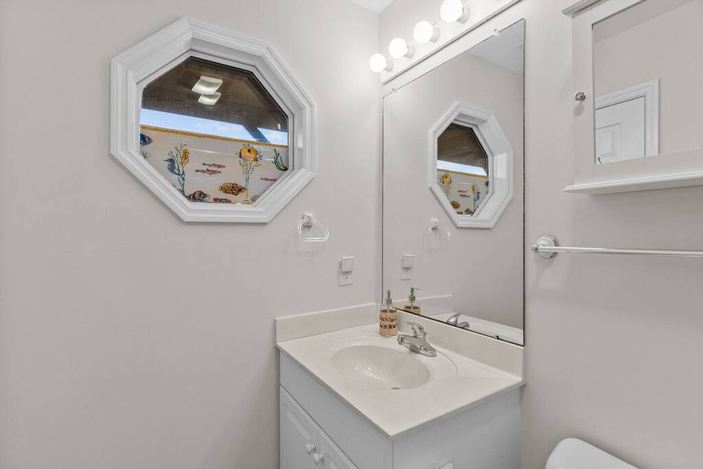 Freshen up in your bright bathroom featuring a charming octagonal window with whimsical underwater artwork that adds character to your space.