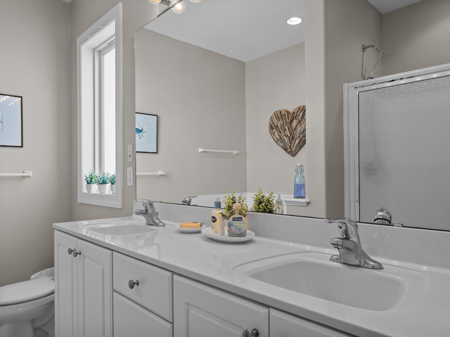 Step into your private bathroom retreat with dual sinks, thoughtful decor, and natural light—perfect for your morning routine.