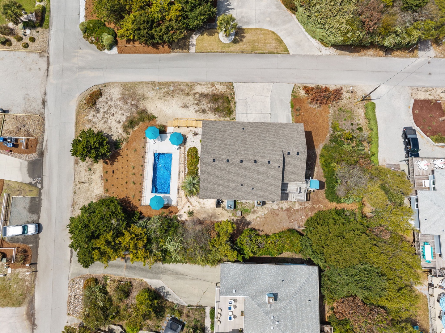 Aerial view of the property showcasing the swimming pool, outdoor seating areas, and residential neighborhood setting.