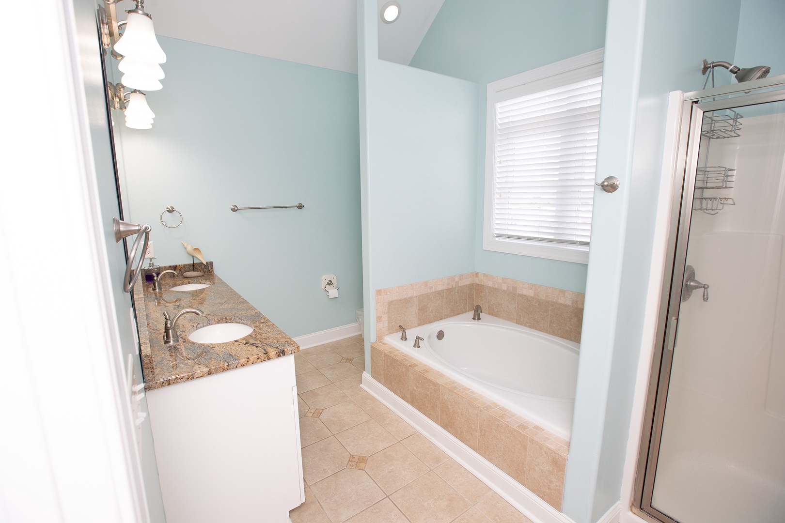 Unwind in your spa-like bathroom featuring a soaking tub, granite vanity, and refreshing coastal colors that create the perfect retreat.