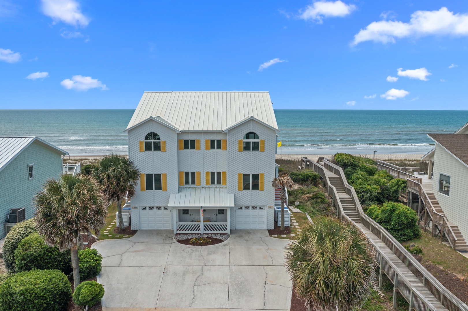 Beachfront duplex with private walkway leading directly to pristine sandy shores and ocean waves.