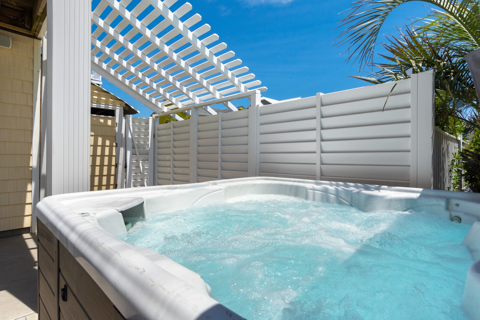Soak your stress away in this private hot tub, where tropical palms and blue skies create your perfect relaxation sanctuary.