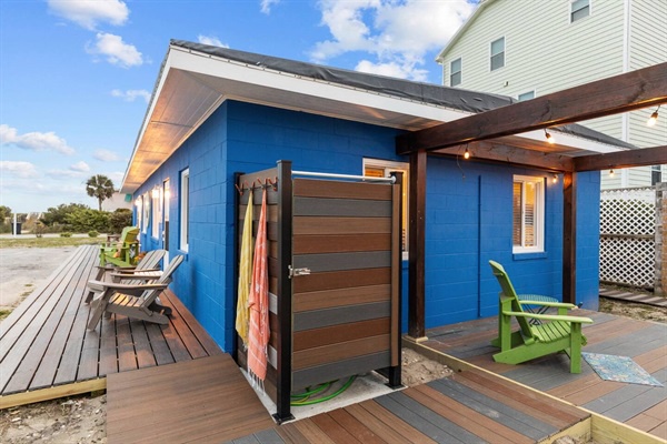 Bright blue beach cottage with modern wood accents and outdoor shower - your perfect coastal retreat awaits.